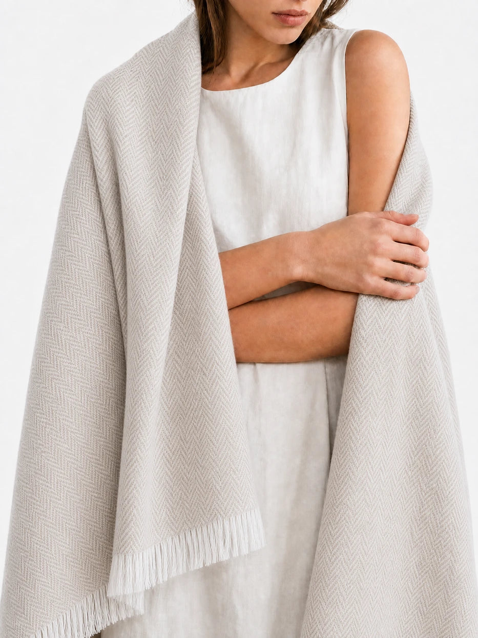 Minimalist close-up portrait shot of model wrapped with CHENZHI khaki herringbone wool throw, fully displays complete full-width herringbone layout and bottom white fringe design, dual function as decorative home couch cover and wearable shawl for indoor & outdoor use