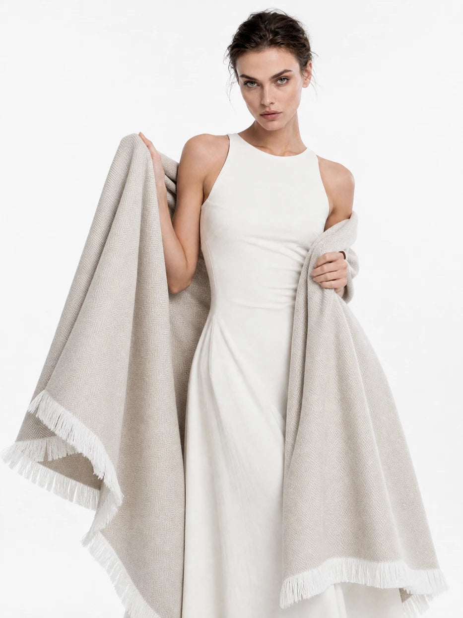 Pure white background half portrait shot of model wrapped with CHENZHI khaki herringbone wool blanket, demonstrates multi-scene usage as wearable shawl, office nap cover, outdoor beach wrap, lightweight silky breathable linen wool blend fabric suitable for all seasons, minimalist wearable home textile for daily rest and travel