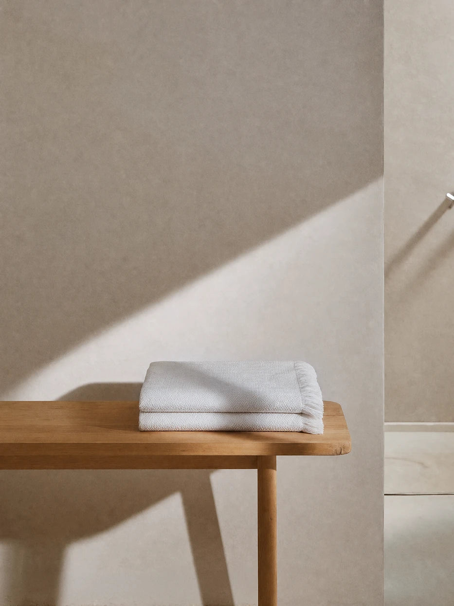 Wabi-sabi full bathroom furnishing layout shot, CHENZHI white herringbone wool throw double folded on solid wood bathroom bench, matched with textured micro-cement wall, plain white textile adds clean soft layered texture to rough hard interior, perfect decor for villa bathroom, homestay washroom, large flat master bath, neutral minimalist interior styling
