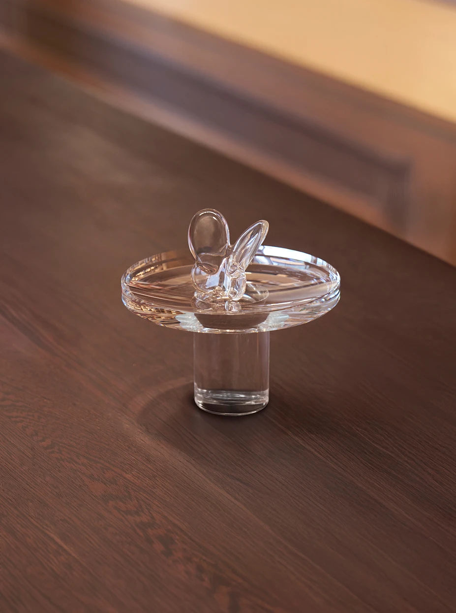 Warm wood furnishing shot of clear crystal butterfly on transparent raised acrylic tray over dark solid wood countertop