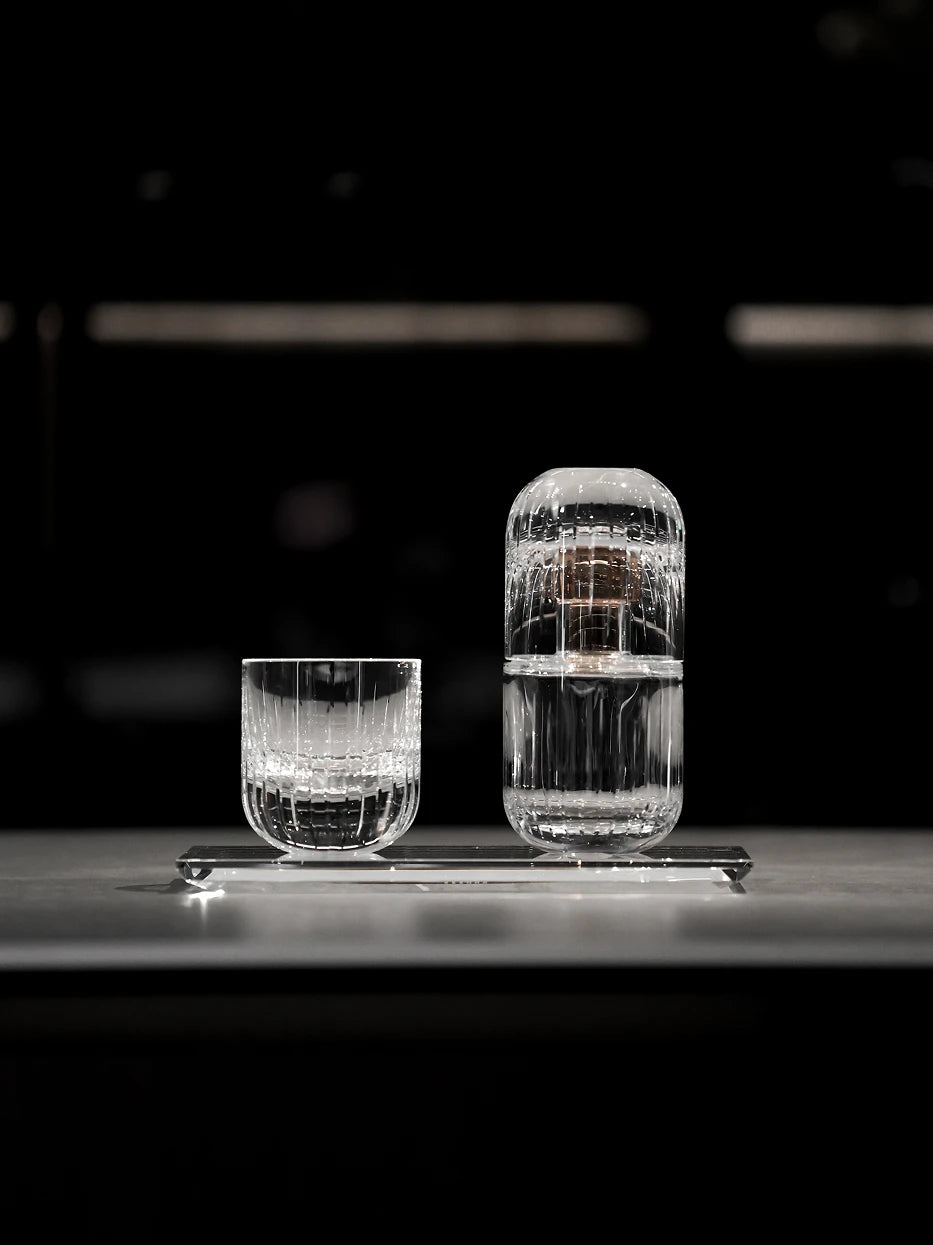Minimal still life close-up of crystal long tray matched with tall & short striped glassware on matte dark countertop