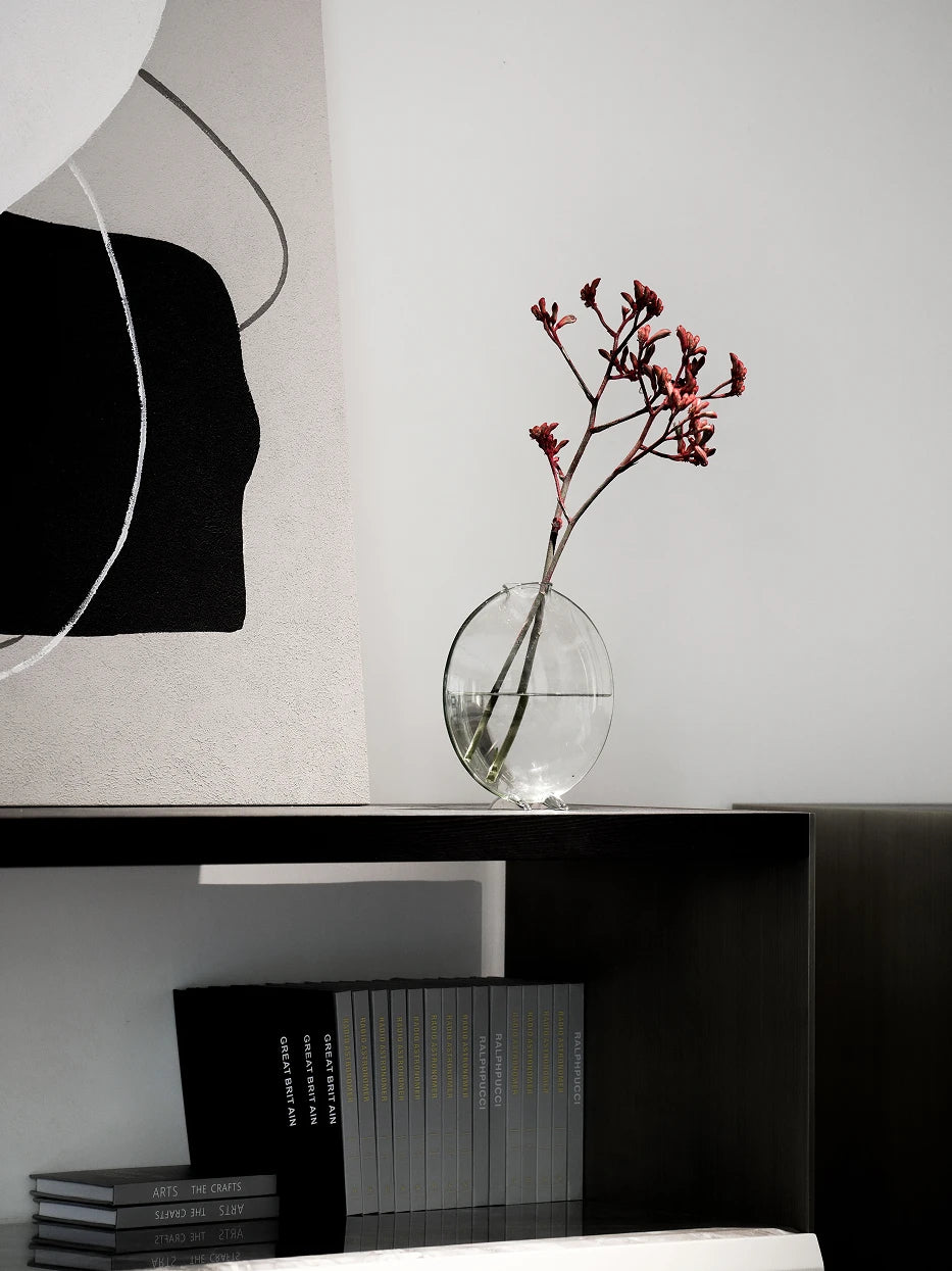 Quiet minimalist study furnishing shot of large Fishmouth vase with dry red branches on dark walnut floating bookcase