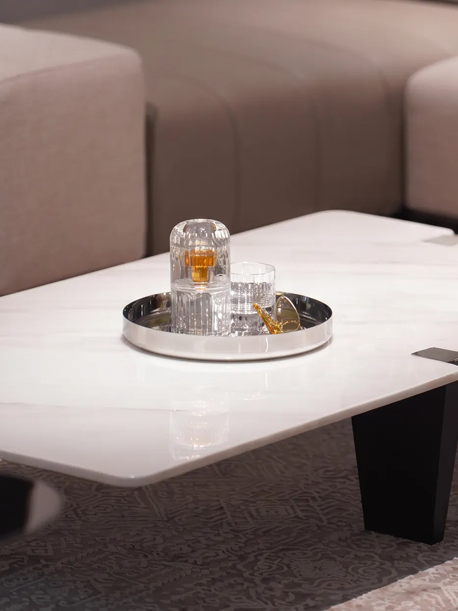Cream-style living room layout shot of HD round stainless steel tray holding glassware and fragrance on white stone coffee table