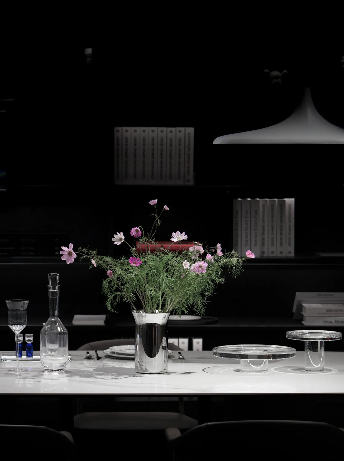 RESONG Home dining table centerpiece decor display, luxury table styling with floral and serveware, featuring SHEDI Collection polished stainless steel vase with fresh cosmos flowers, STARLIGHT Collection high-transparency crystal cake stands, XUYU hand-carved crystal decanter, ERYA porcelain dinnerware and Baijiu glass set. Mirror-polished metal & clear crystal, suitable for modern luxury dining room decor, high-end home centerpiece styling, boutique restaurant table arrangement