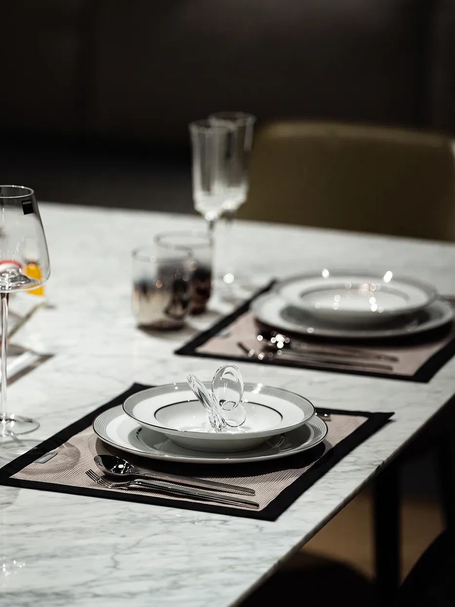 Light luxury hotel western table layout shot of stacked ERYA black silver plate set, matched with clear glass butterfly ornament, vertical striped glass tumblers and full metal cutlery on white marble tabletop