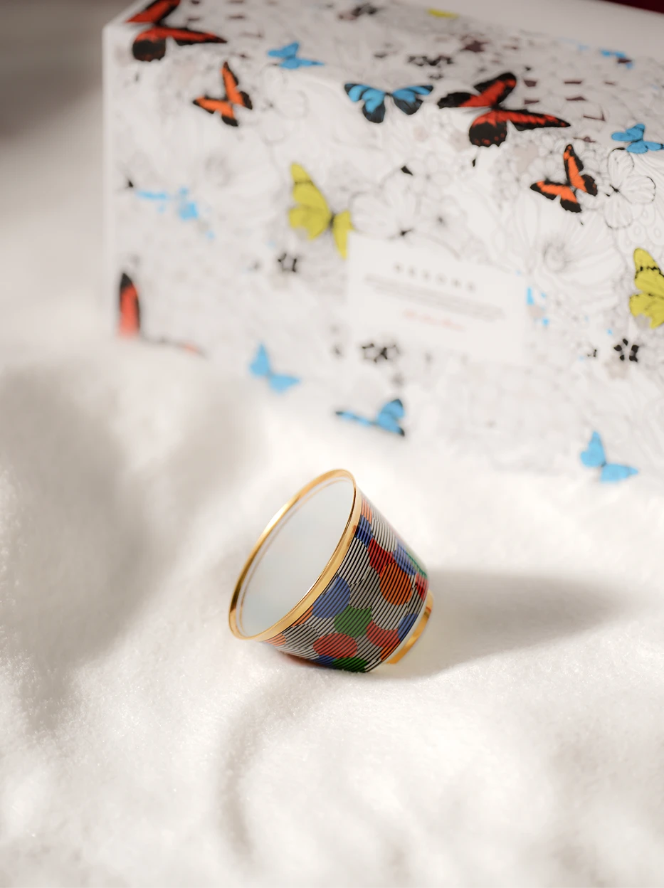 Festive gift-style still life of GUOYUE Composition gold-rim ceramic cup laid upside down on soft cotton texture, butterfly printed gift box as background for holiday display