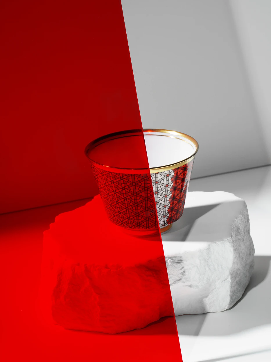 Artistic contrast still life of GUOYUE Gradient ceramic cup placed on rough stone block, split red-grey backdrop creating dramatic light and shadow texture