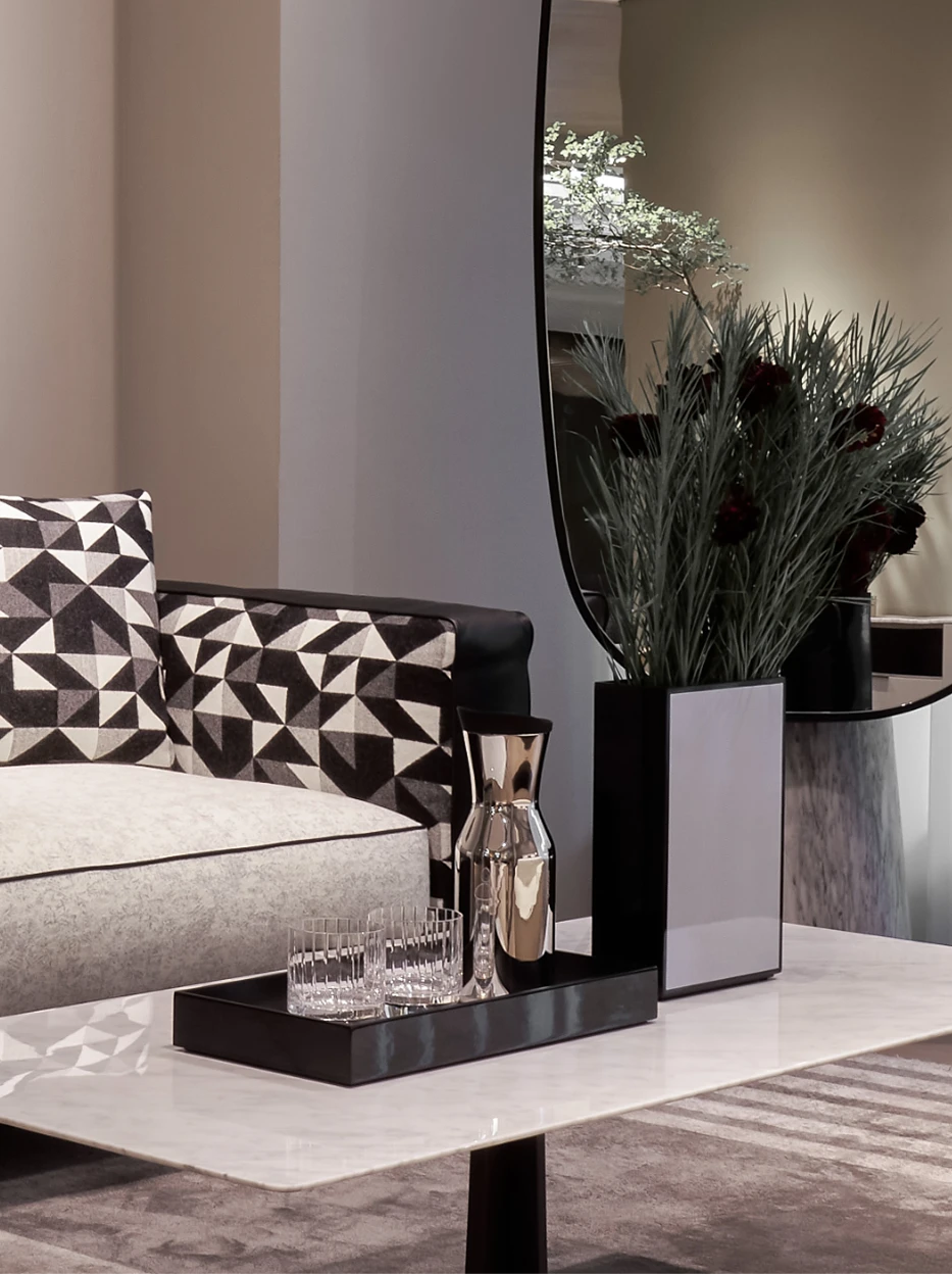 Full living room decor shot of SHEDI mirror steel carafe set on long black metal tray, matched with vertical striped glass cups and silver vase beside geometric fabric sofa
