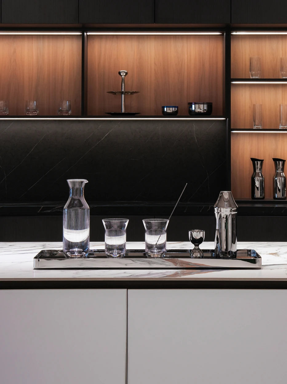 Light luxury sideboard full bar display shot of SHEDI cocktail set matched with matching carafe and vertical striped glass tumblers on rectangular metal tray