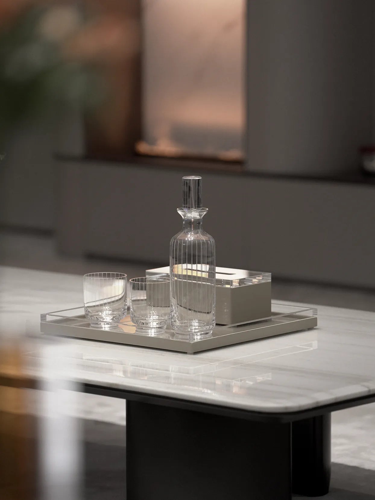 Minimal modern living room lifestyle shot of XUYU crystal whiskey serving set on light rectangular metal tray, matched with silver curved vase holding red & white roses plus eucalyptus on white marble coffee table