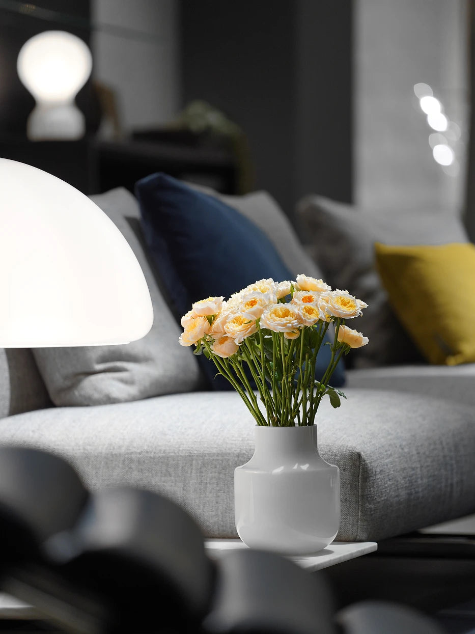 Soft minimalist living furnishing shot of minimalist vase B full of pale yellow roses on floating white side table next to light grey fabric sofa