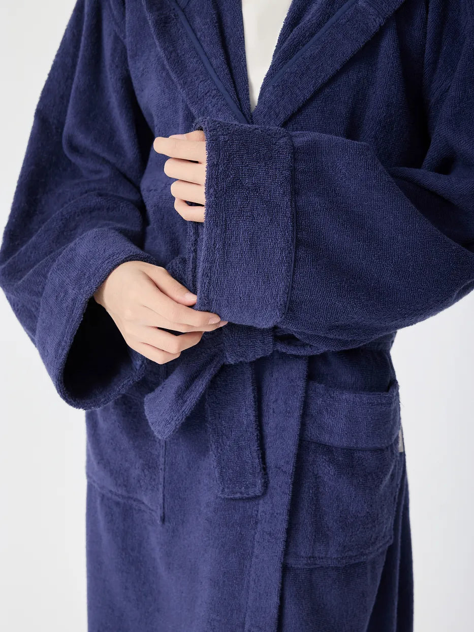 Close-up of RESONG navy blue hooded terry cloth bathrobe cuff, hands adjusting folded sleeve showing thick absorbent cotton texture and trim detail, white background