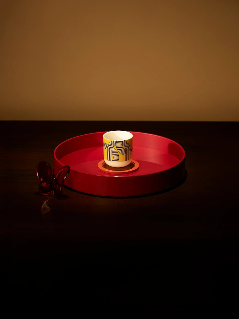 Luxury bar layout shot of medium red round tray holding two fluted crystal wine goblets on dark matte table