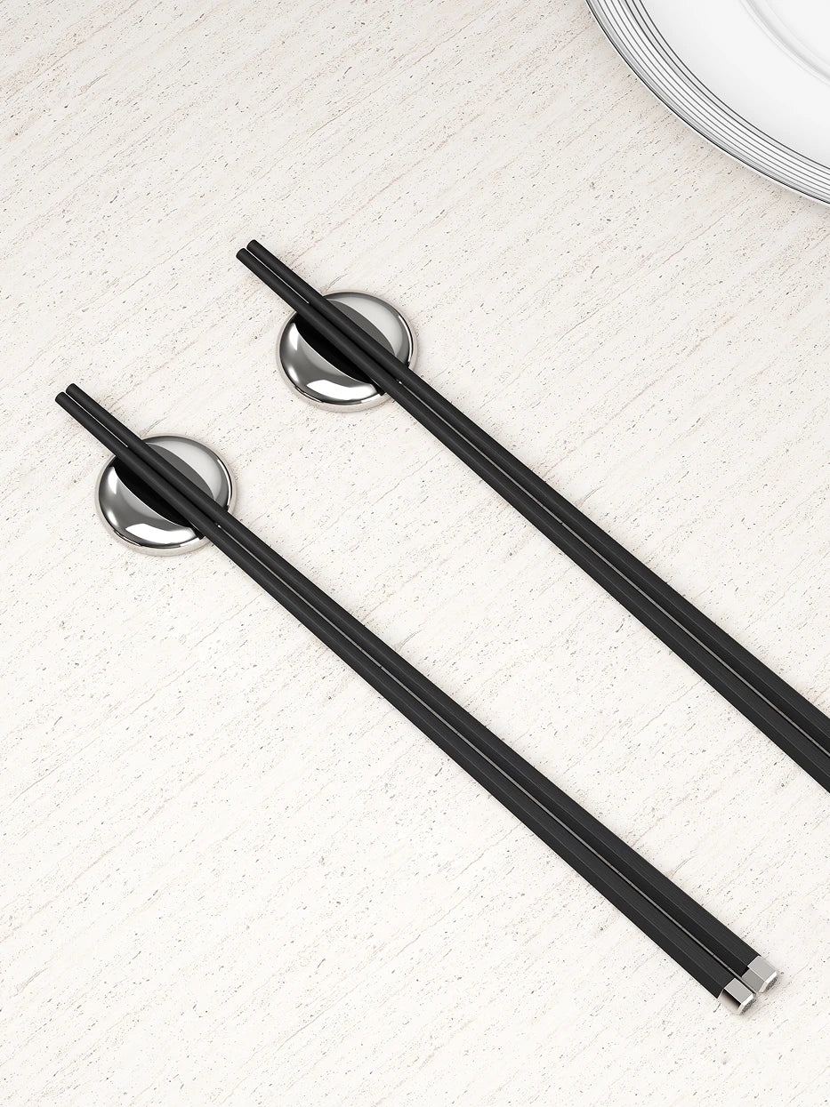 Daily Chinese table layout shot of PAVILION ebony silver chopsticks matched with LINGLONG plum blossom stainless steel rests on light speckled stone tabletop