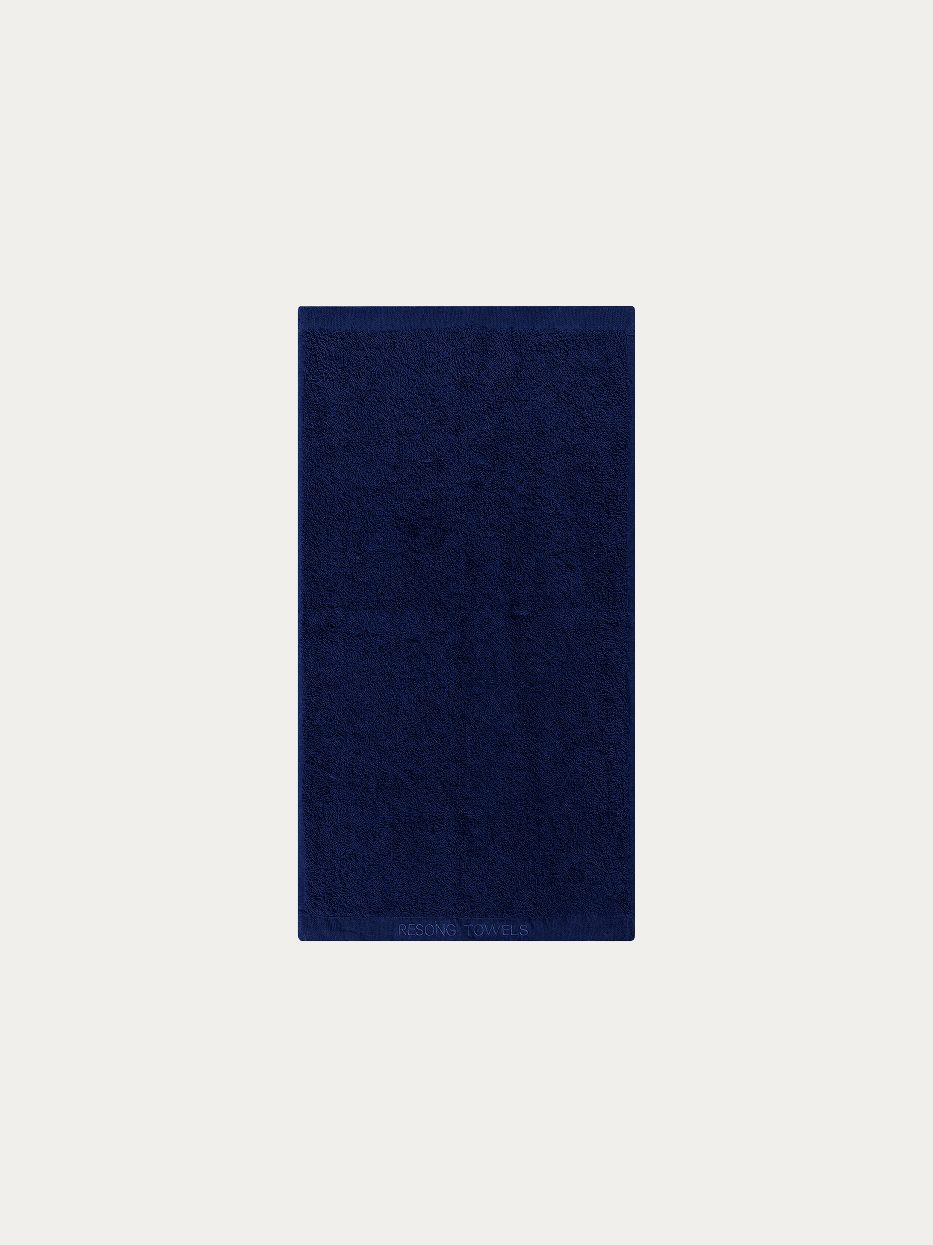 Official flat lay product shot of R Collection navy blue cotton bath towel on pure off-white background, full-body wrap size 1400×700mm, 640g heavyweight thick cotton terry loop, matching tone subtle embroidered RESONG TOWELS logo on hem, stain-resistant absorbent large towel for business hotel & men household gift set