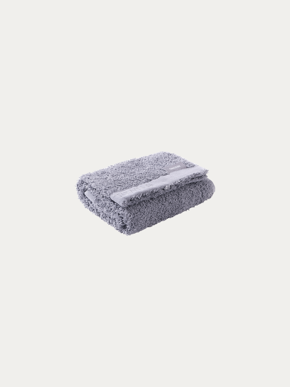 Official folded product shot of R Collection grey cotton face towel on pure off-white background, oversized 750×410mm, 200g heavyweight thick terry, woven band embroidered with TOWELS logo, water-absorbent facial towel for hotel & gift box matching