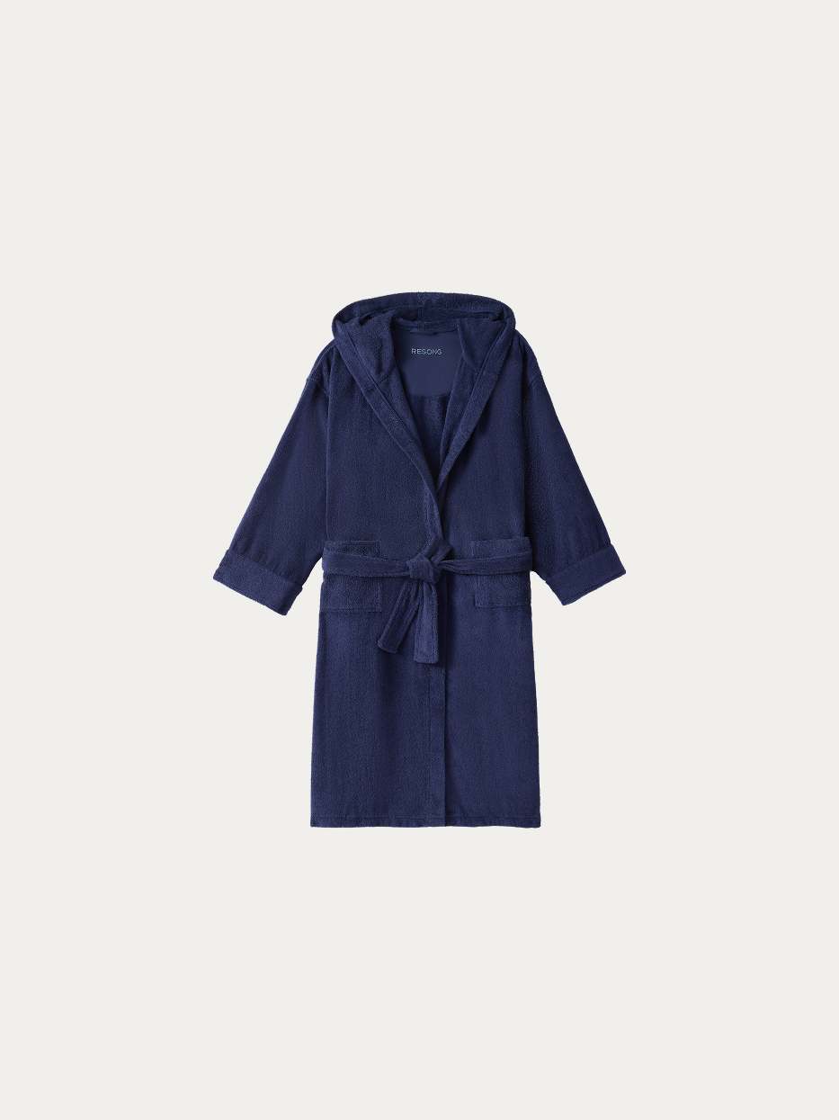 Official hanging product shot of R Series navy blue hooded bathrobe on pure off-white background, 100% thick high-density cotton terry fabric, integrated three-dimensional hood, kimono V-collar, matching fabric wide waist tie, dual large side patch pockets, 120cm long water-absorbent bathrobe for home, hotel and spa use