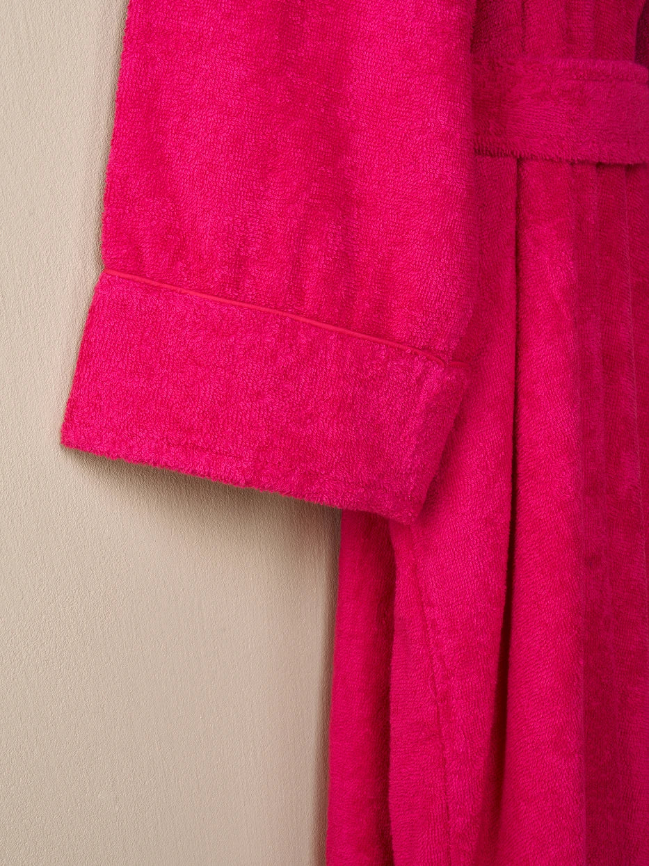 Macro close-up of folded cuff wrapped edge of R Series rose red cotton bathrobe, uniform neat same-color cotton lock stitching, double-layer fitted terry fabric, displays wash-resistant precise sewing craft