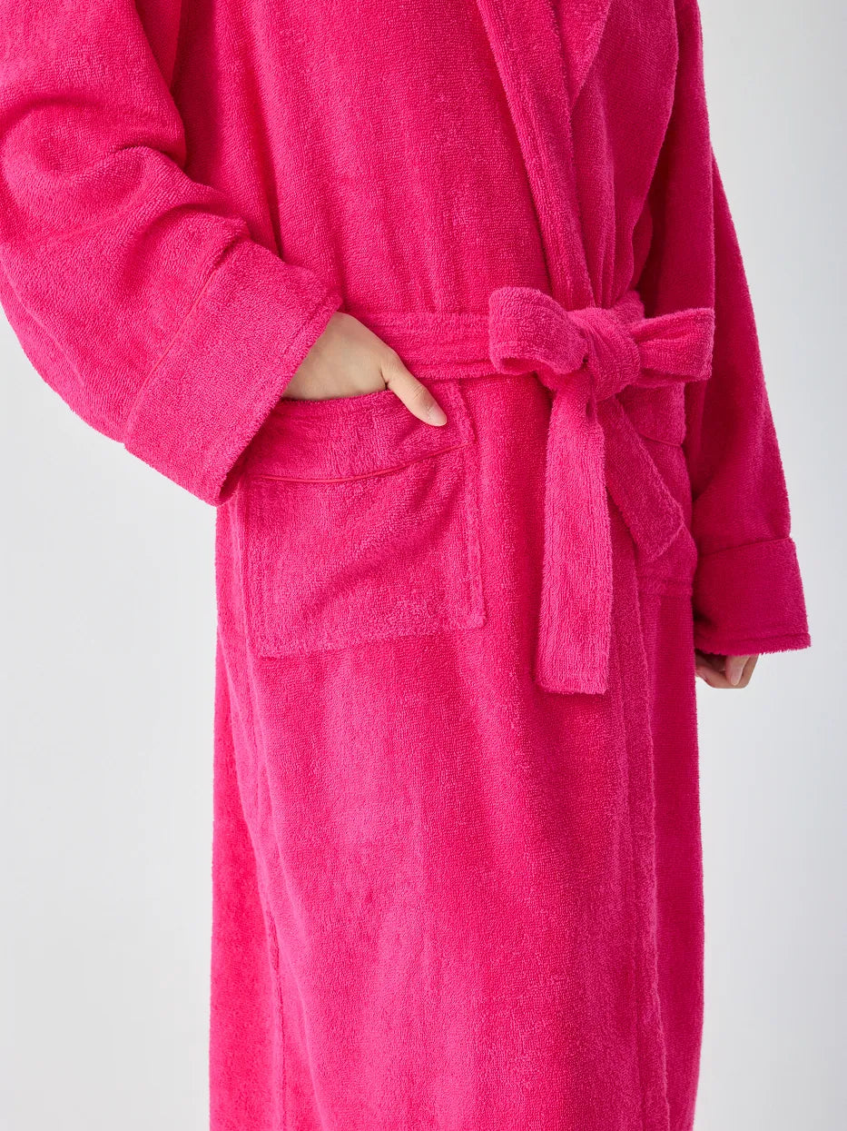 Close-up of RESONG rose red hooded terry cloth bathrobe showing patch pocket and matching belt tie, hand resting in pocket, soft absorbent cotton texture, white background
