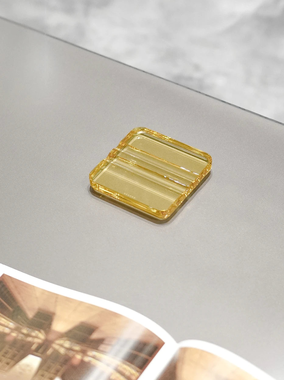 Retro minimalist furnishing shot of amber RUIYING cigar holder laid on art book atop light grey matte marble table