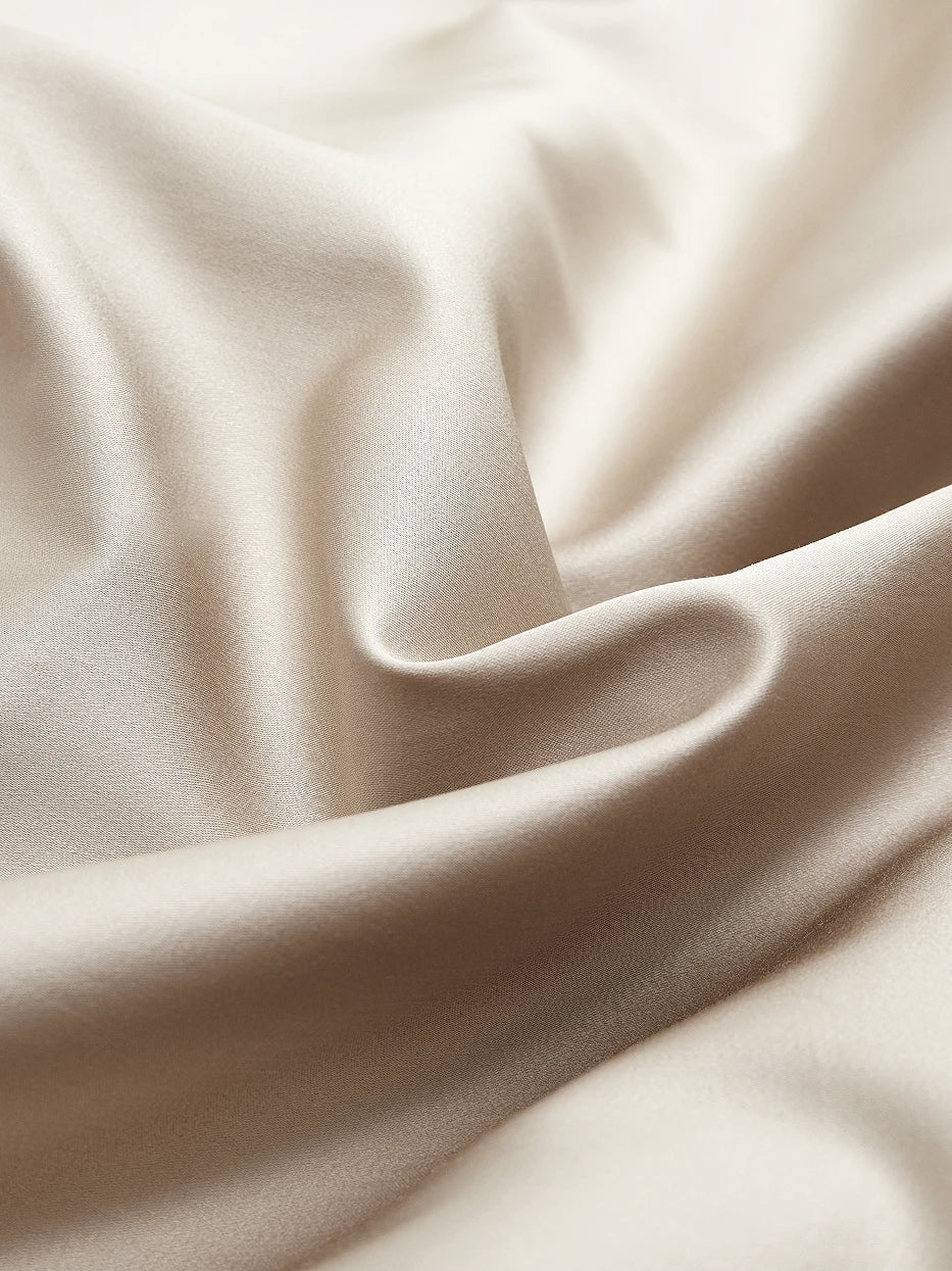 Soft natural light close-up shot of SHUMIAN champagne gold silky cotton fabric, showing smooth matte satin texture, tight 480TC high-density weaving
