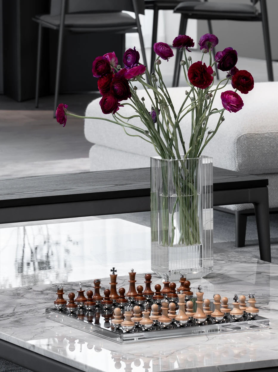 Monochrome minimalist living furnishing shot of TORY mirror chess set matched with striped crystal vase & purple ranunculus on dark grey gloss marble coffee table