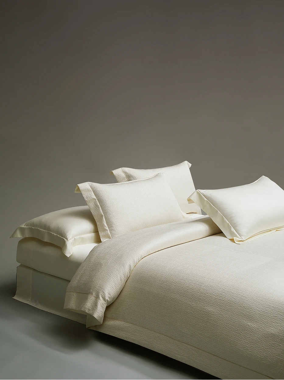 Close-up furnishing shot of full Vintage cream bedding pillow set with two styles of pillowcases, showing thick jacquard fabric & delicate herringbone stitch edge