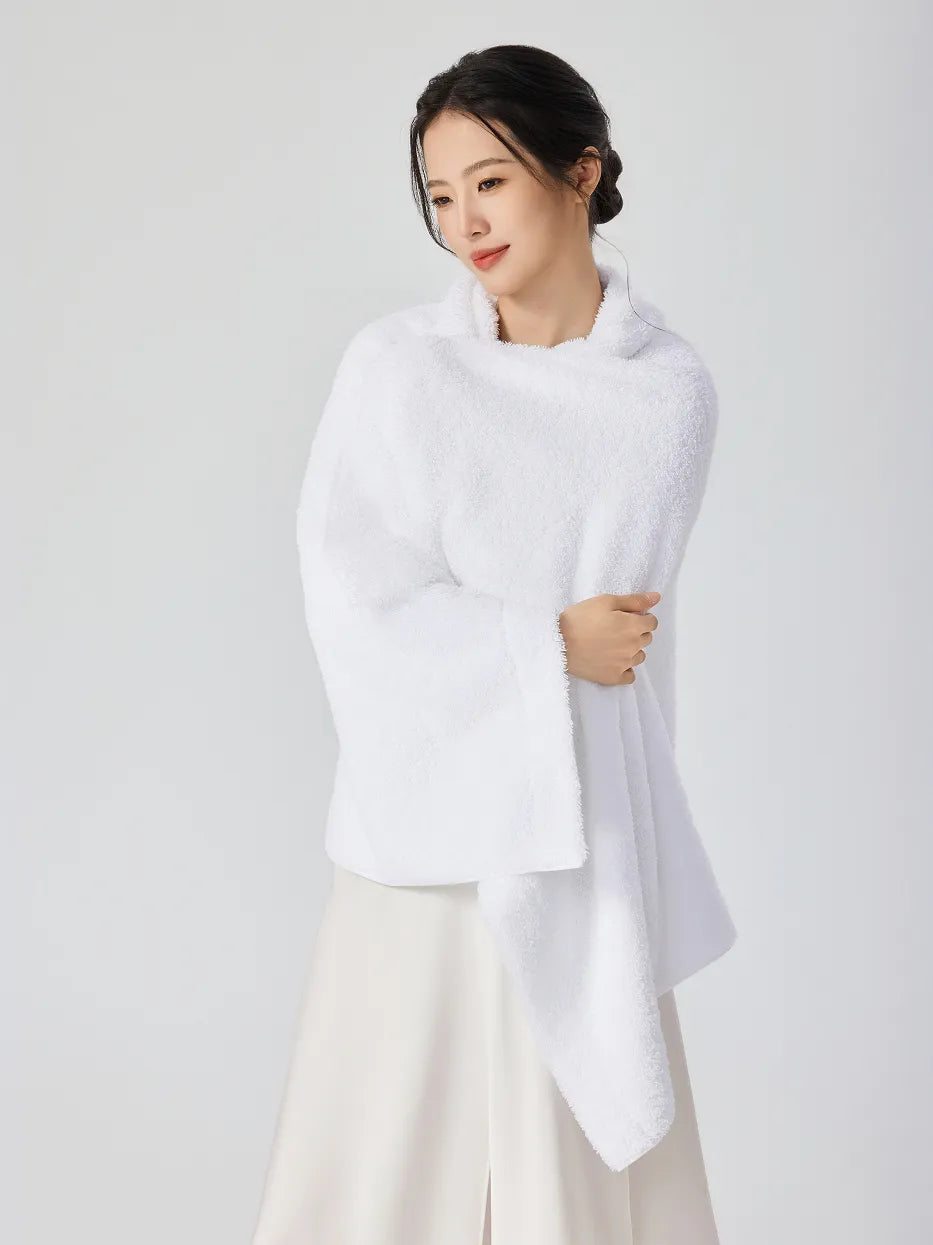 Woman wrapped in RESONG white cotton terry bath towel like a cozy turtleneck shawl, arms crossed holding towel, soft fluffy absorbent bath towel on model, white studio background