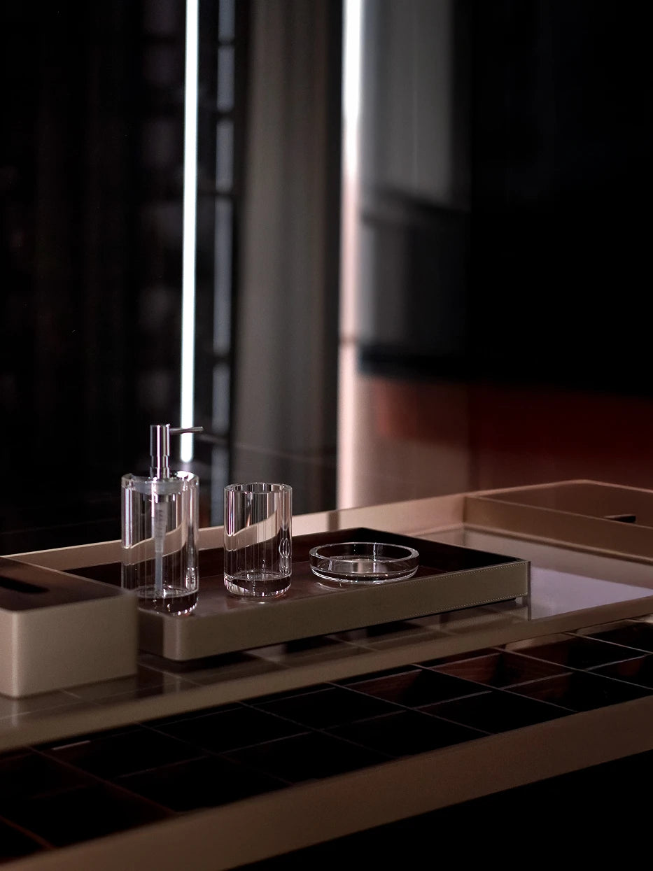 Dark minimalist bathroom furnishing shot of full XUYU crystal set (soap dish + lotion bottle + reed diffuser) on light leather vanity tray