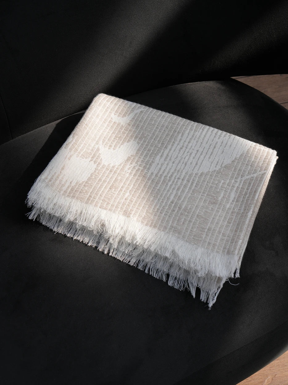 Minimalist interior still shot of folded YUNQI textured linen throw placed on curved black accent armchair on solid wood flooring, warm soft contrast between light beige textile and dark furniture, lightweight breathable linen blend fabric without bulky texture, great decor for entryway lounge, reading nook, hotel rest corner, modern dark tone interior matching