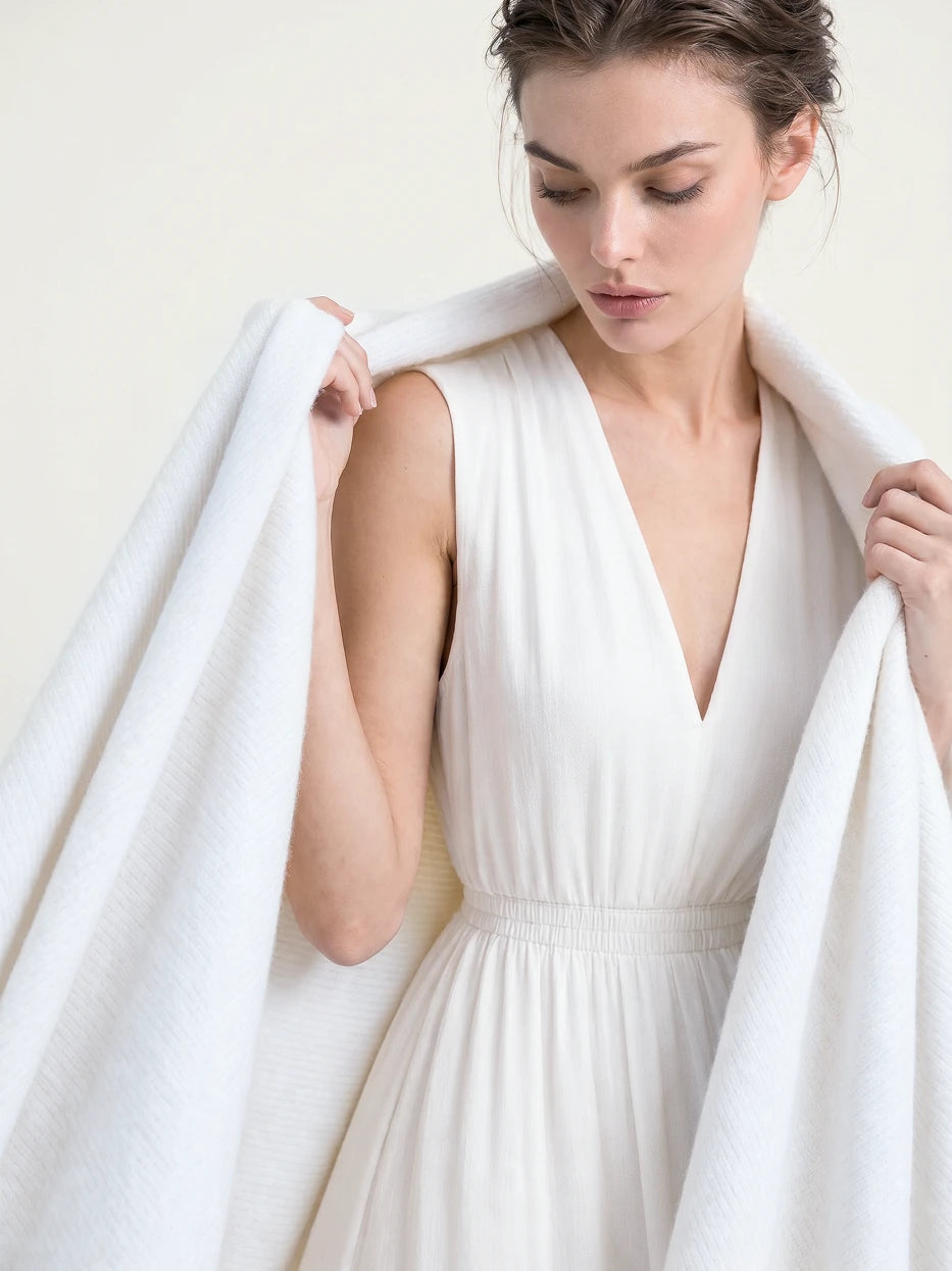 Pure white background half portrait shot of model wrapped with BERLIN white ribbed stripe blanket, demonstrates multi-scene usage as wearable shawl, office nap cover, daily travel wrap, lightweight soft wool blend fabric suitable for all seasons, minimalist wearable home textile for daily rest and travel