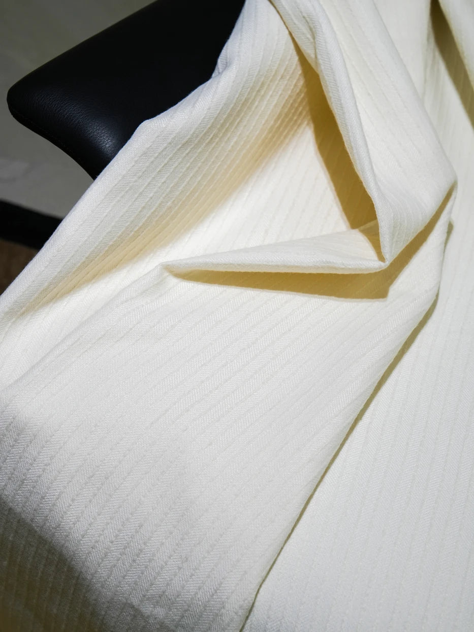 Extreme drape texture close-up shot of BERLIN wool blend white throw blanket, showing dense vertical ribbed stripe texture and seamless neat finished edge detail, visible soft wool touch and silky drape of viscose fiber, displays premium multi-fabric knit craft and delicate ribbed tactile texture for home textile product display