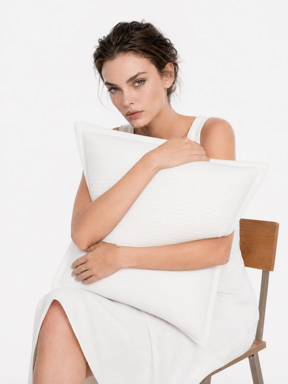 Pure white background half portrait shot of model hugging BERLIN white ribbed stripe cushion, displays plump fluffy support effect of natural goose feather filling, highlights soft comfortable touch and delicate vertical stripe fabric texture, minimalist wearable home textile display for daily rest scene