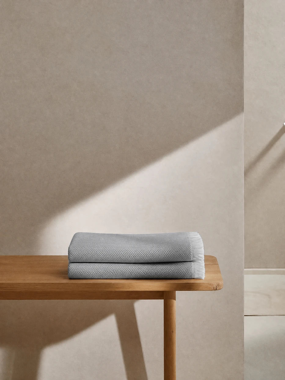 Wabi-sabi full bathroom furnishing layout shot, CHENZHI gray herringbone wool throw double folded on solid wood bathroom bench, matched with textured micro-cement wall, cool gray textile adds soft layered texture to rough hard interior, perfect decor for villa bathroom, homestay washroom, large flat master bath, neutral minimalist interior styling