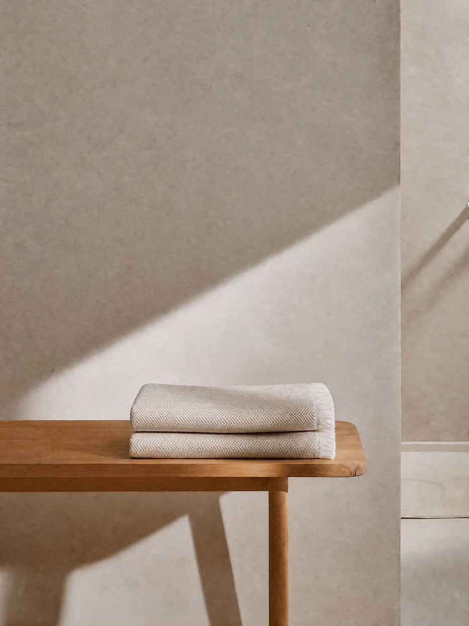 Wabi-sabi full bathroom furnishing layout shot, CHENZHI khaki herringbone wool throw double folded on solid wood bathroom bench, matched with textured micro-cement wall, warm khaki textile adds soft layered texture to rough hard interior, perfect decor for villa bathroom, homestay washroom, large flat master bath, neutral minimalist interior styling