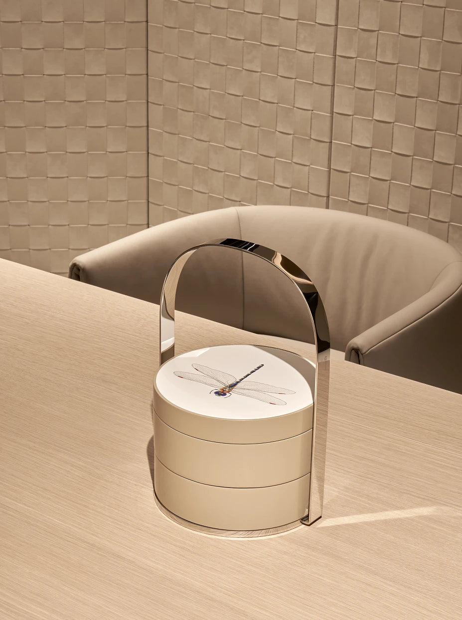 Minimalist study furnishing shot of khaki double dragonfly box on light wood desk with curved beige fabric armchair