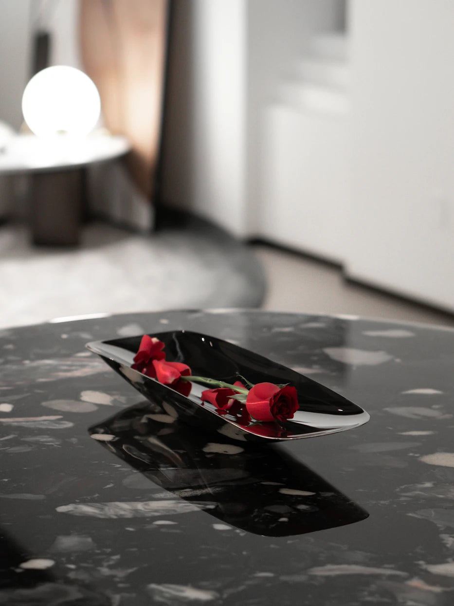 Luxury flower layout shot of HD long stainless steel plate filled with red roses on black patterned marble coffee table
