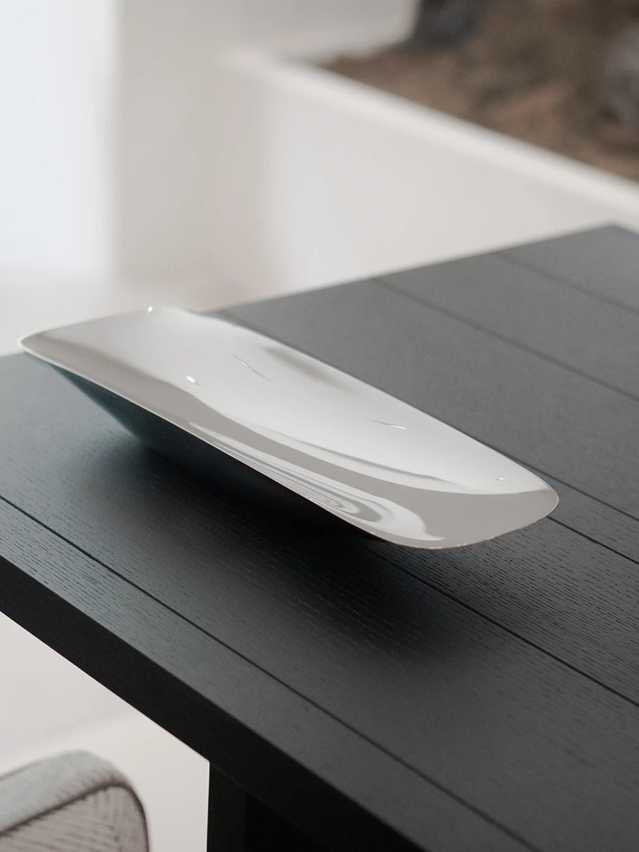 Minimal home furnishing shot of empty HD long metal plate on light black wood tabletop against pure white interior backdrop