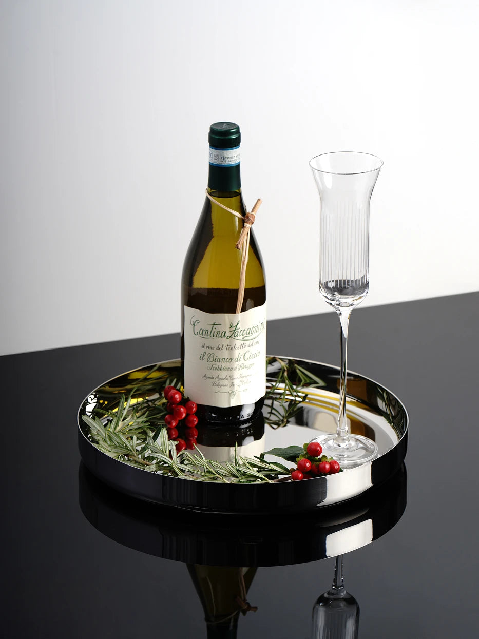 Luxury wine tasting still life shot of HD round stainless steel tray filled with white wine bottle, goblet and herbal decoration on glossy black countertop