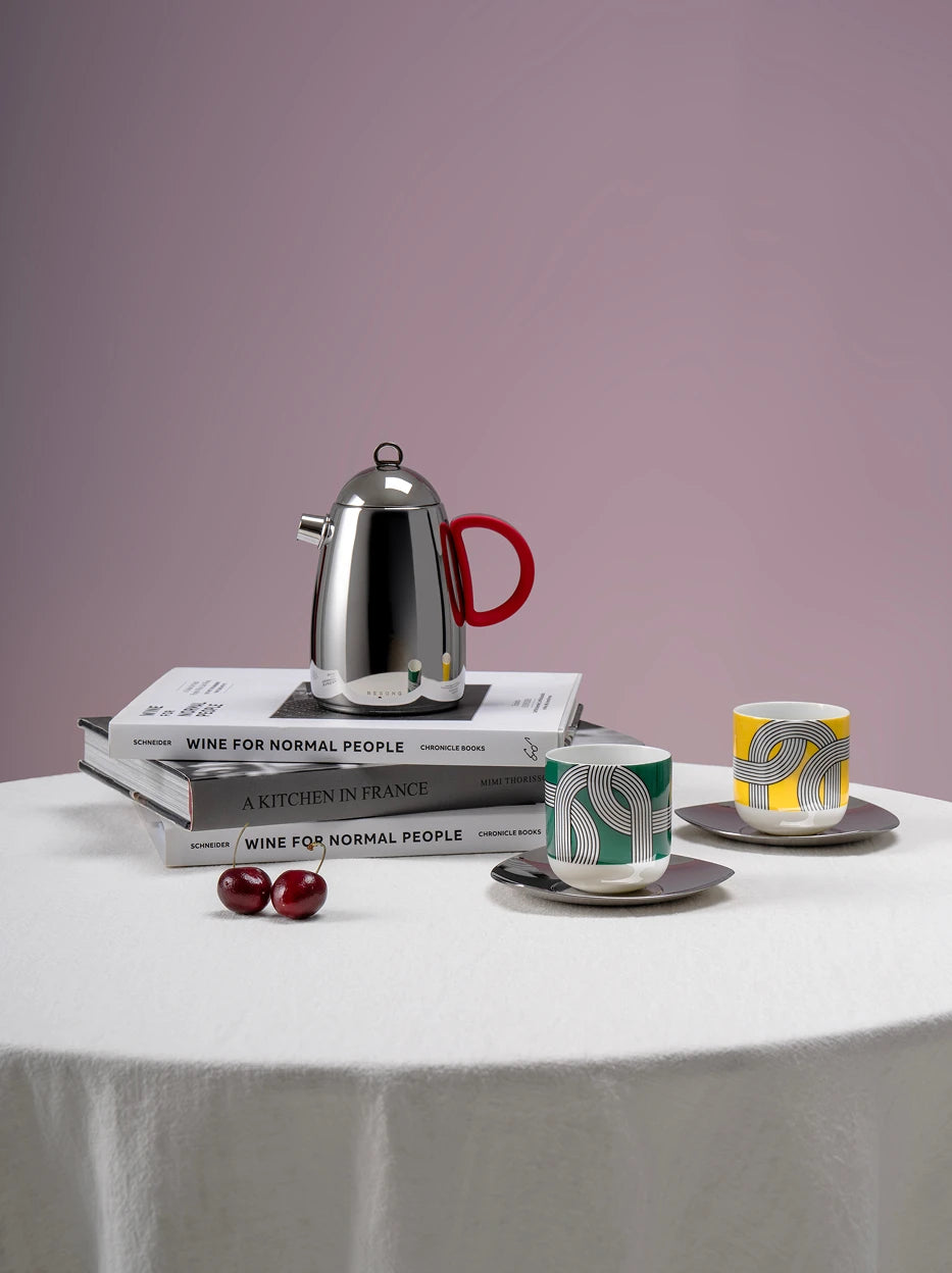Elegant indoor lifestyle shot of full ALK serving set laid on white round table, matched with stacked wine books and fresh cherry fruit, soft pale pink gradient wall backdrop