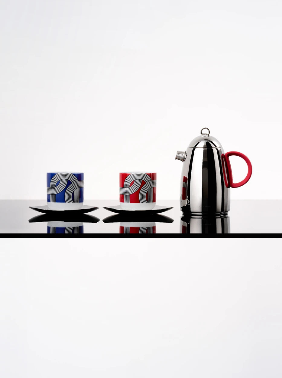 Minimal symmetrical studio display of complete ALK red & blue ceramic cup sets with stainless steel pot, reflective light gray glossy tabletop with full mirror reflection