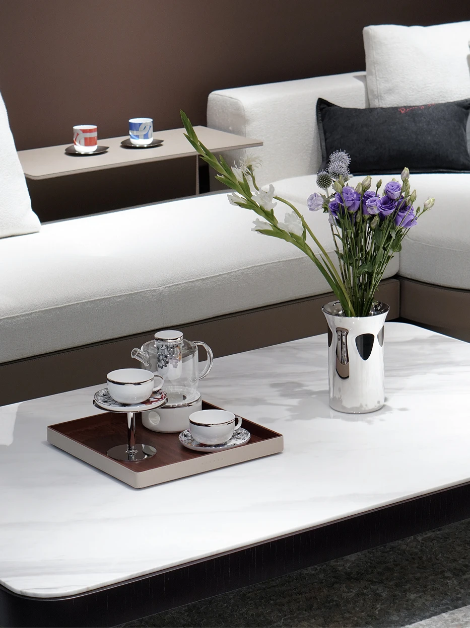 Full modern luxury living room shot of BUTTERFLY WHISPER brewing tea set, matched with purple flower vase on white marble coffee table beside fabric sofa