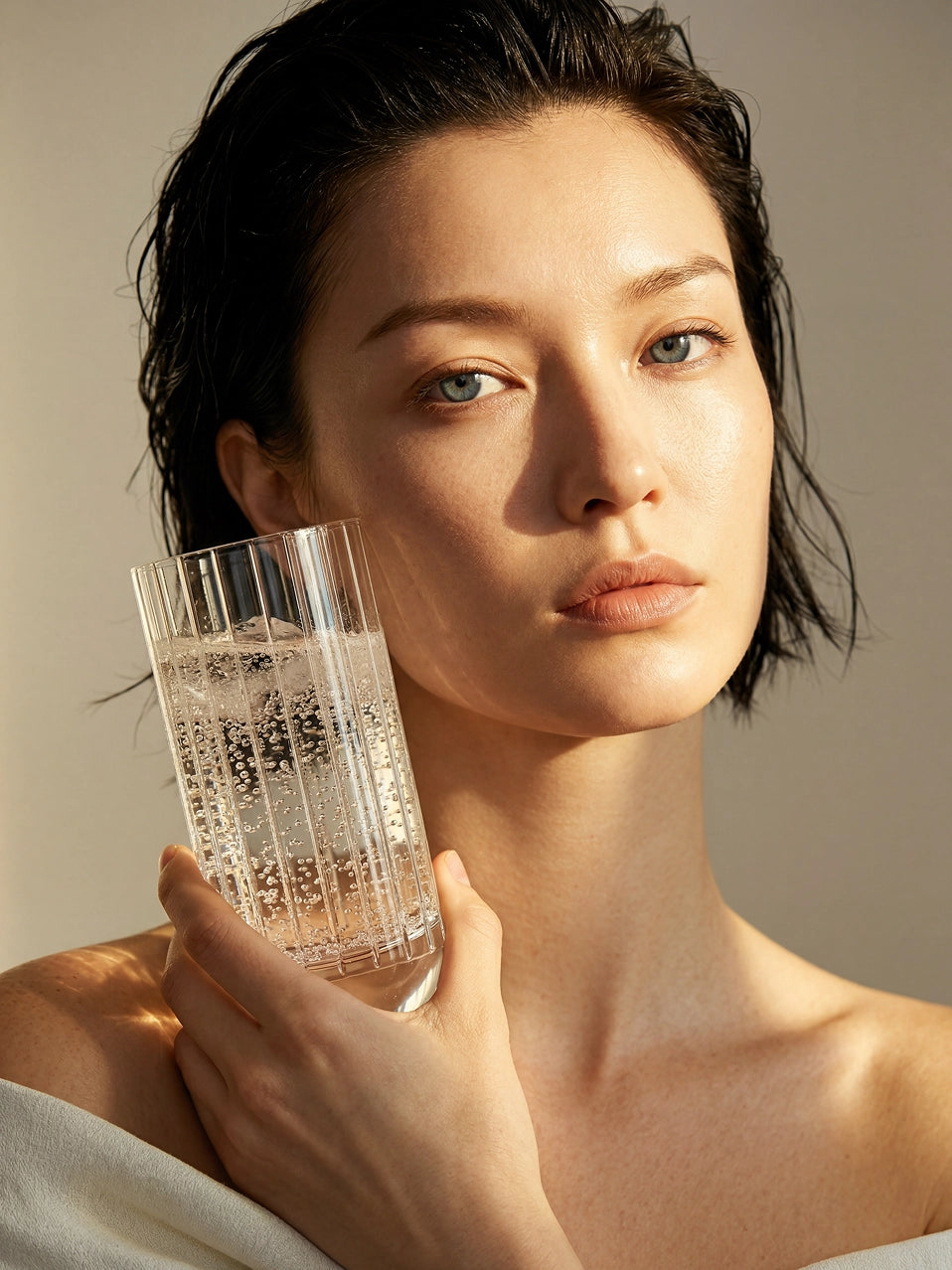 Model holding RESONG HOME DEWDROPS Tall Glass (Pair), dew drop ribbed tall crystal highball glass with sparkling water, warm soft light luxury home bar tableware