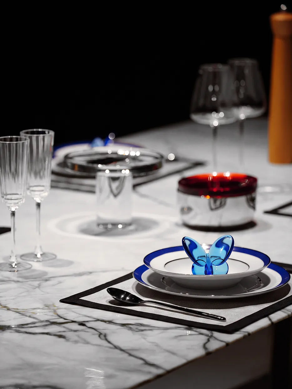 Light luxury western table layout shot of ERYA large blue rim plate matched with matching soup bowl, blue glass butterfly ornament and vertical striped tall glasses on white marble tabletop