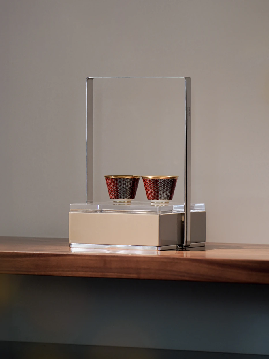 Light luxury exhibition shot of two GUOYUE Gradient gold-rim ceramic cups placed inside acrylic metal display stand, wooden table background for home showroom display