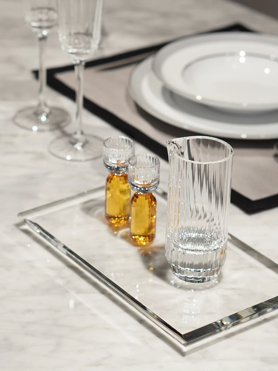 Elegant dining lifestyle photo of HAOYING amber baijiu crystal set on thick clear crystal tray, matched with western ceramic tableware on white marble tabletop