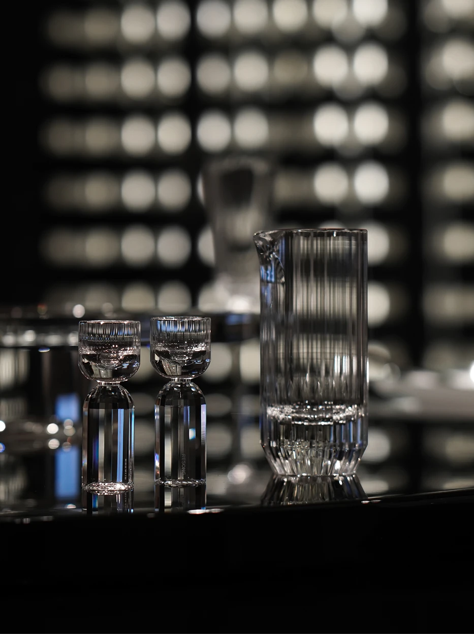 Luxury studio shot of HAOYING crystal baijiu pitcher and dual shot glasses, reflective black tabletop with soft circular bokeh light background
