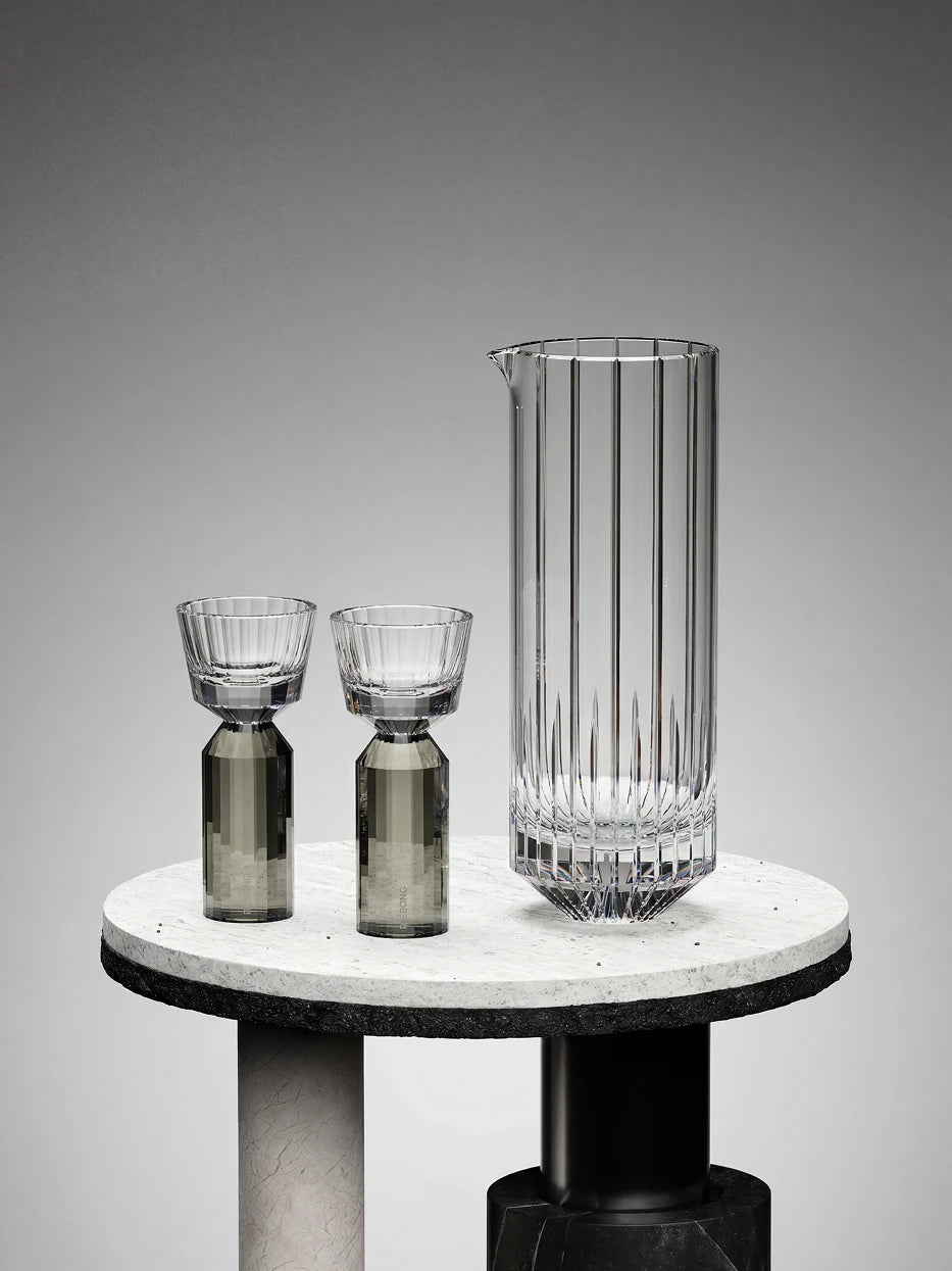Minimal luxury studio display of complete HUAZUN smoke gray baijiu crystal set on round two-tone stone display stand, matte gradient gray background