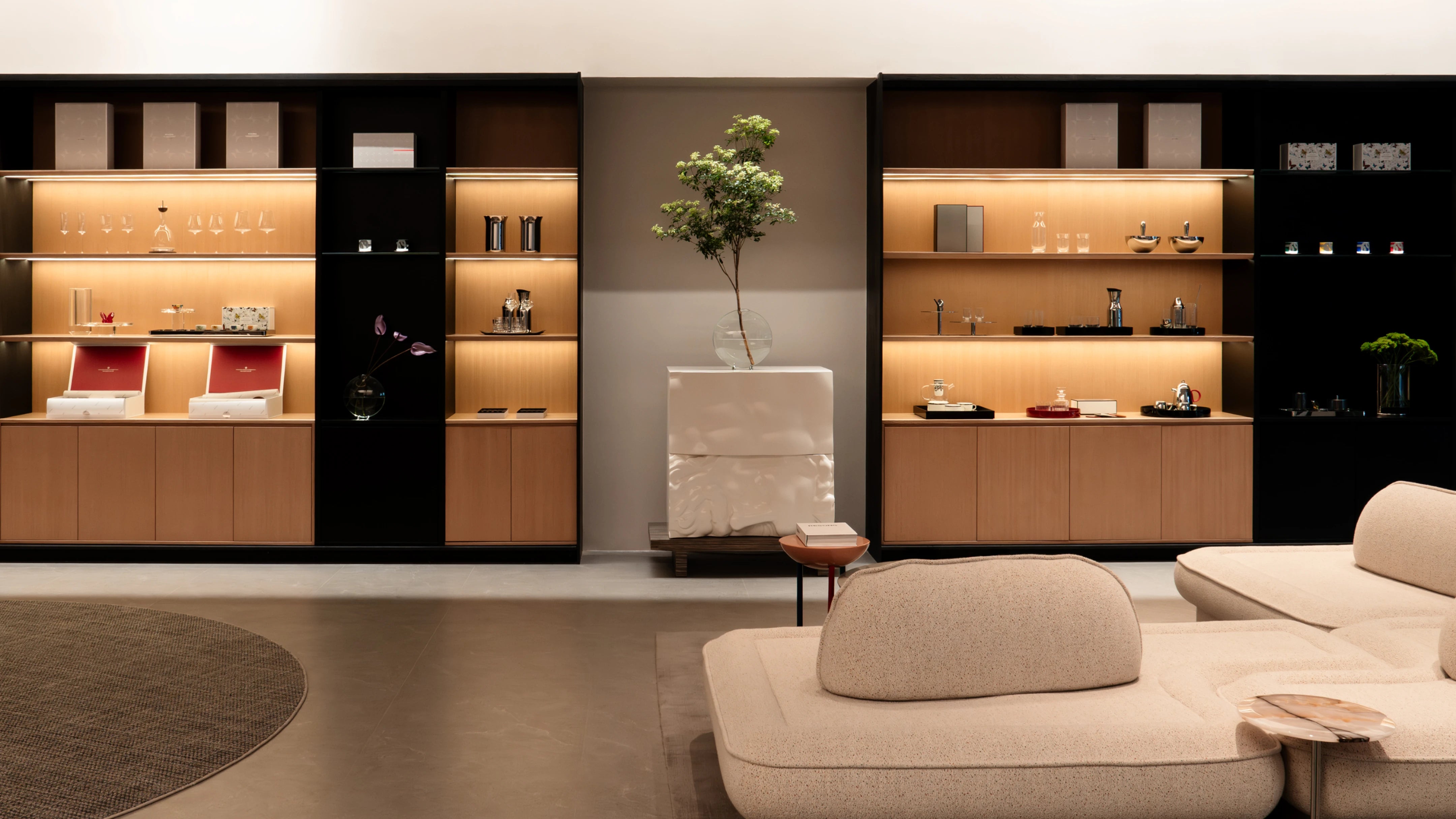 RESONG Home premium living lounge showroom full panorama, dual wooden & black framed built-in LED display cabinets with modular sofa decor, featuring 1833, XUYU Hand-Carved, ALK, UNDERGLAZE MULTICOLORED Ceramic, QINGYING Vase, DRAGONFLY Lacquer Storage, GUOYUE Tea, TRIUMPH Whiskey and PAIS Storage collections. Premium crystal, ceramic and lacquer homeware, ideal for villa living room decor, model home soft furnishing, luxury retail showroom, residential home bar design
