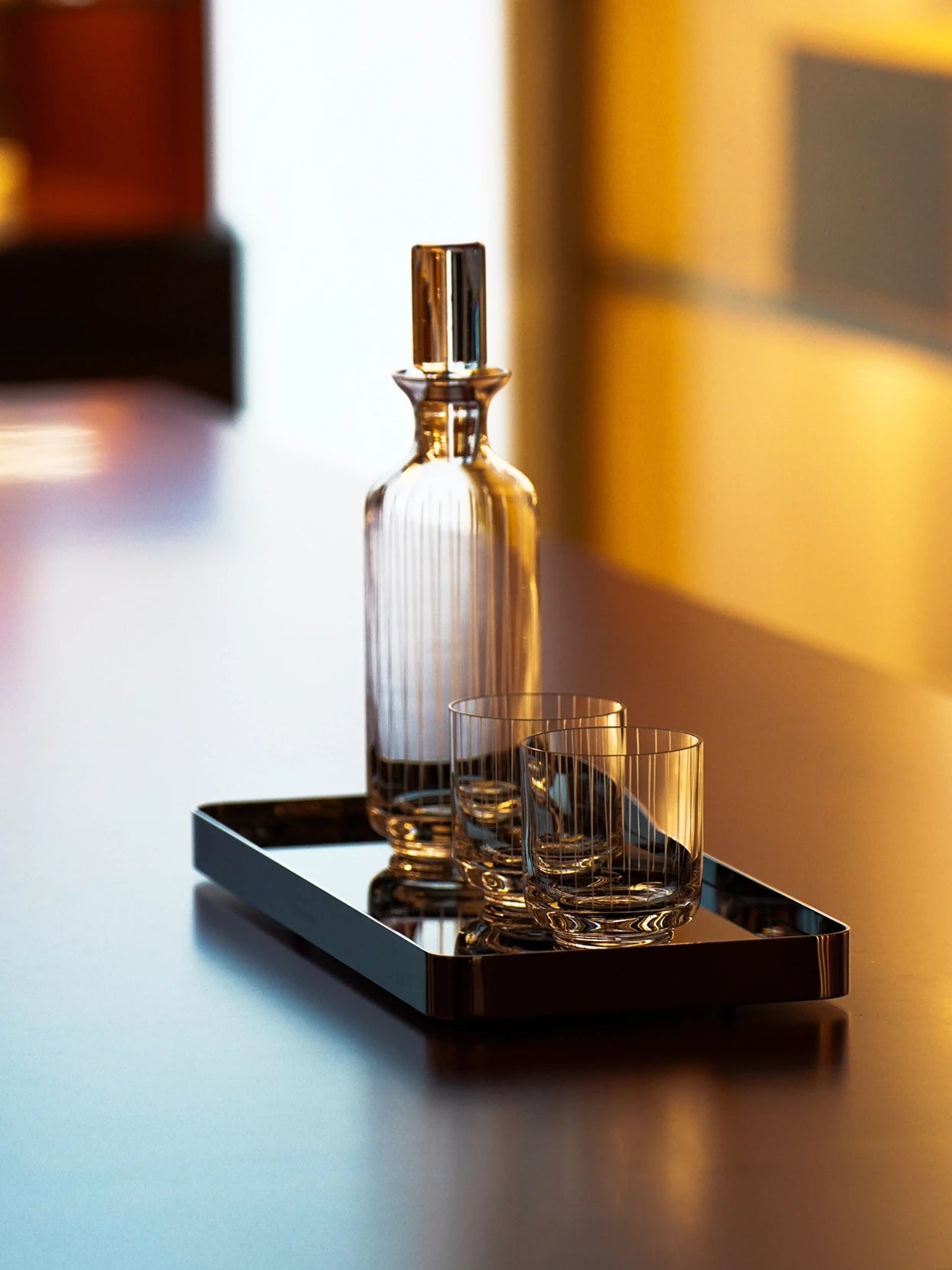 Warm luxury bar lifestyle shot of full XUYU ribbed crystal whiskey set placed on reflective black metal rectangular tray, soft golden ambient indoor lighting, minimalist table display